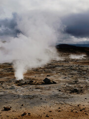 Steaming geothermal landscape under dramatic cloudy skies in Iceland