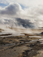 Steaming geothermal landscape under dramatic cloudy skies in Iceland