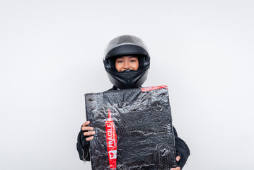 Female delivery courier holding fragile parcel wearing motorcycle helmet and uniform