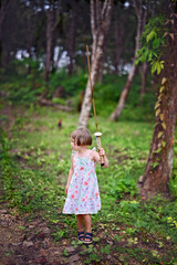 Naklejka premium Kid girl plays in the woods