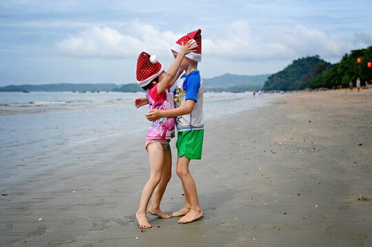 kids in Santa hat on the beach - Powered by Adobe