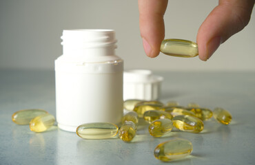 Male hand holding fish oil on the table. Fish oil capsules, omega 3, omega 9, vitamin D, vitamin E