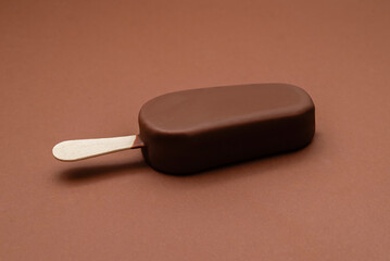 chocolate ice cream on a stick on a brown background