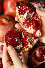 Hands open the pomegranate, separation into parts, pomegranates grains