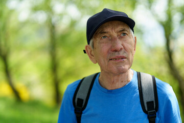 Portrait of an elderly man with a backpack in the park.