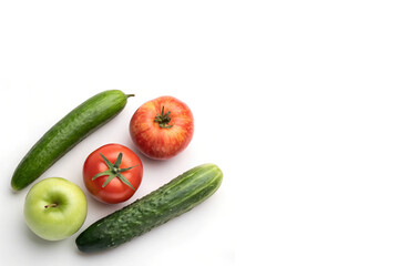 Collection of Fresh Fruits and Vegetables Including Cucumbers, Apples, and Tomato Positioned Left Side on White Background with Copy Space