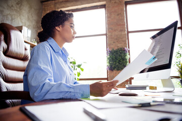 Professional African American businesswoman working at office desk with focus and determination during daytime