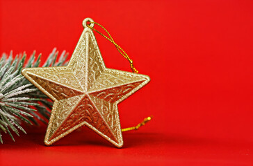 golden christmas star ornament with pine branch on red festive background