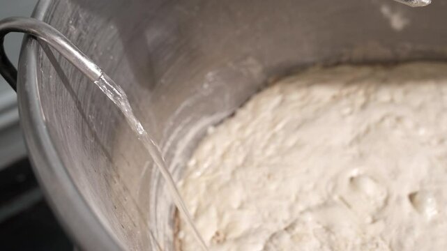 Water supply to the dough starter container in the dough mixer in the bakery. An industrial mixer for kneading dough. One of the stages of bread dough preparation