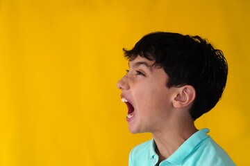 young teenager in profile with yellow background screaming © Inspiraciones