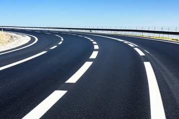 Obraz premium Smooth Curving Road under Clear Blue Sky Ideal for Travel, Adventure, and Transportation Themes, Capturing Freedom and Journeying in a Serene Landscape