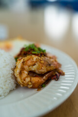 Stir fried shrimp with garlic and chili served together with steamed rice and find egg on white plate