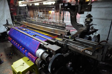 The weaved blue saree rolled up in the back of the powerloom machine