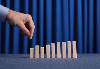 Hand Reaches for Wooden Blocks on Blue Background in Strategic Scene