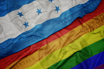 waving colorful flag of honduras and gay rainbow flag on the dollar money background. finance concept.