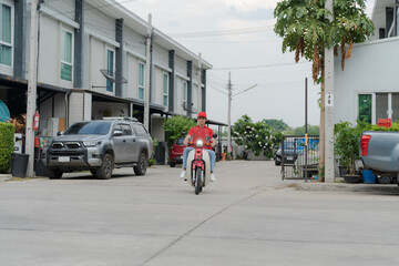 Delivery rider on red motorbike with insulated food box parked outdoors