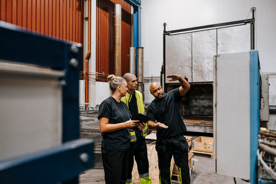 Mature worker gesturing while talking with male and female coworker in steel industry