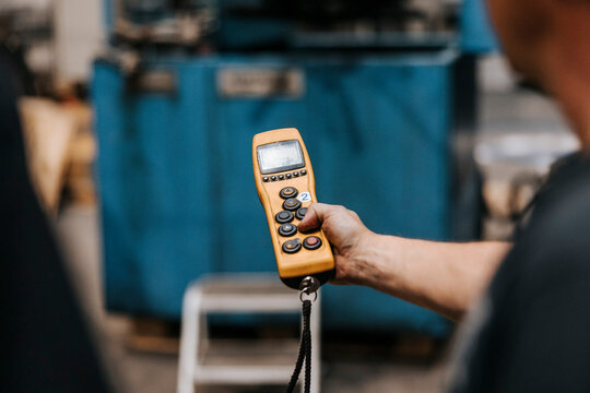 Hand of male worker holding remote control at factory
