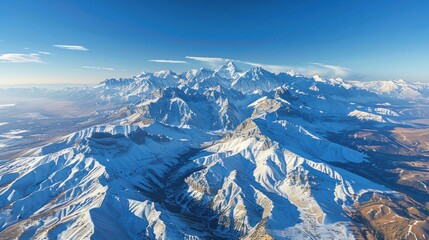 Obraz premium Aerial View of Majestic Snow-Capped Mountain Range Under a Clear Blue Sky