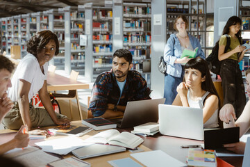 Multiracial male and female university students studying in library
