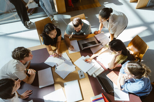 High angle view of multiracial male and female students doing group assignment in library at college