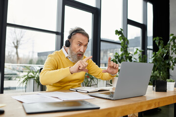 Senior man actively participating in a virtual conference while seated at a desk.