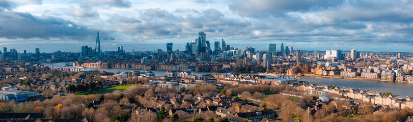 Naklejka premium The image captures an aerial view of London with The Shard on the left, Canary Wharf on the right, and Tower Bridge in the distance over the River Thames.