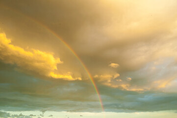 Sunset sky landscape, stunning multi-colored rainbow after rain on the sunset sky and golden clouds