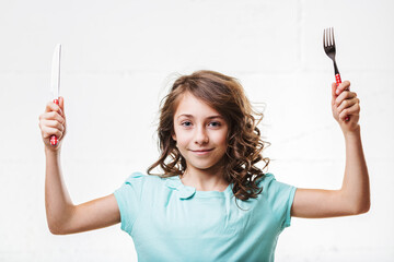 Young girl raising cutlery with confidence