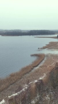 A December day in the Latvian countryside in Latgale, a meadow, a country road and Lake Siver can be seen.