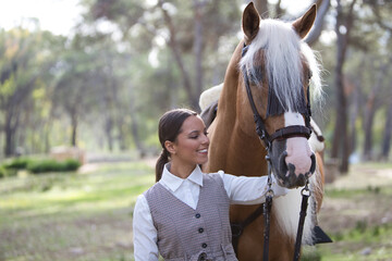 portrait of equestrian woman, young and beautiful, lovingly holding her purebred brown horse with blond mane by the head and joining her face together. The woman is happy. Love for the horse. - Powered by Adobe