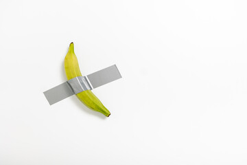 A male banana is securely attached to a pristine white wall using duct tape. This artwork...