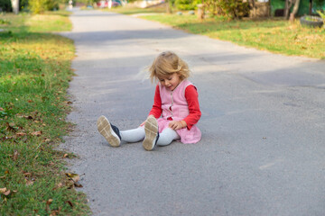 The child fell on the road and hit her leg. Selective focus.