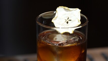 Closeup cocktail whiskey in Old fashioned with cube ice decorated dried sliced apple on top making special drink list, advertisement focusing alcohol refreshing showcase copy space at club. Vinosity.