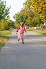 A child runs and jumps on the street along the road. Selective focus.