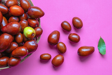 Jujube fruit  ( Ziziphus jujuba ) in small basket on pink background. Copy space