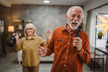 senior man sing karaoke on microphone with senior woman dance behind