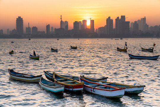 Sunrise over Mumbai skyline with fishermen boats in the foreground.