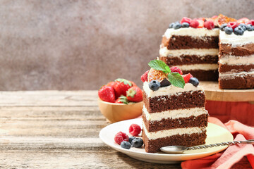 Piece of delicious chocolate sponge cake with berries served on wooden table, space for text
