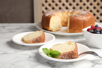 Freshly baked sponge cake, mint and berries on white marble table, closeup