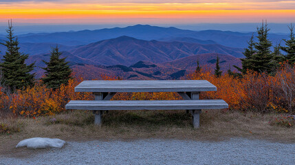 Obraz premium serene wooden table stands against breathtaking mountainous scenery at sunset, surrounded by vibrant autumn foliage and distant peaks