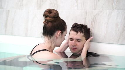 Couple sharing intimate moment in indoor pool gentle touches and tender smiles capture serenity and connection.