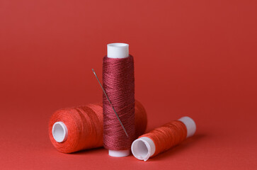 Red thread spools with needle background with copy space for text close-up flat lay top view