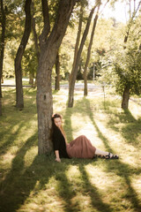 Girl in nature in the park. Curly girl in a linen dress. Sunny day and beautiful sunlight. Warm photos of a girl enjoying nature in a good mood. Walking alone with yourself and the beauty of nature.