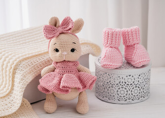 Fototapeta premium Variety of knitted toys. Bunny and baby booties. Handmade soft toys.
