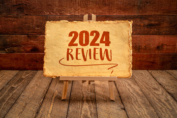 2024 year review - easel sign with antique paper against rustic wood, end of year business concept