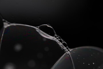 Transparent liquid surface, bubbles of thick liquid, silver reflection on dark background, gray colours
