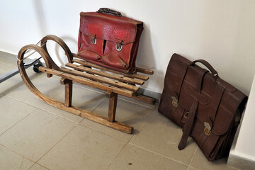 Old wooden retro sled and two leather school bags.