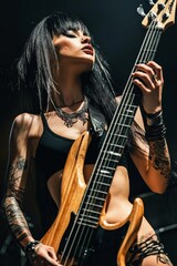 Obraz premium Portrait of a rock girl holding Bass Guitar: A shot shot of a female in grunge rock attire, on her knees, holding an electric bass guitar.