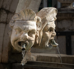 Closeup of the ancient macarons (masks) sculpted in the historical da Ponte fountain, Preseren...